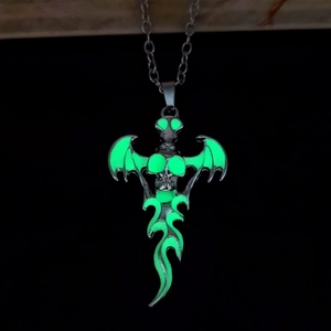 Close-up of gothic glowing skull pendant with bat wings emitting green light at night