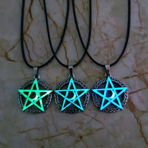 Macro detail of three luminous celtic knot pendants glowing in green, sky blue, and dark blue
