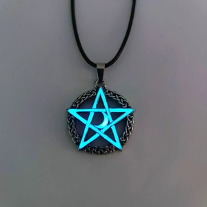 Close-up of glowing star and moon pendant with blue luminescent material and silver frame