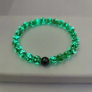 Detail shot of green luminous crystal beads with glowing flakes and black accent bead