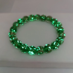 Detail view of healing luminous green glass beads bracelet with sparkling gold sand effect