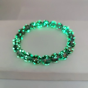 Close-up of luminous star glass beads glowing in the dark on an elastic bracelet