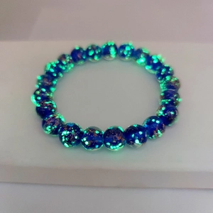 Macro shot of dark blue glowing glass beads with gold sand and green luminous effect