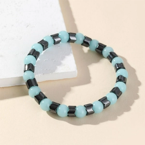 Luminous light blue beaded bracelet with black V-shaped accents on a textured stone