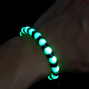 Luminous beaded bracelet glowing green in the dark with black spacer beads for stress relief