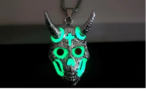 Détail macro montrant l'effet lumineux vert du collier crâne de bélier dans l'obscurité