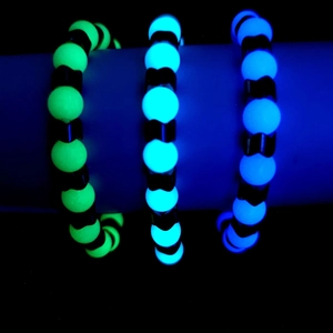Macro shot of glow-in-the-dark beaded bracelets in neon green, ice blue, and deep blue colors