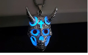 Détail macro d'un pendentif crâne de bélier lumineux avec yeux en strass rouges et lueur bleue