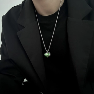Dettaglio di una collana con ciondolo a conchiglia luminosa su un outfit con blazer nero