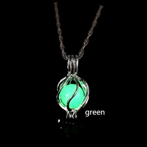 Macro detail of planet pendant glowing green in dark with silver cage structure