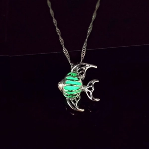 Gros plan du pendentif poisson tropical lumineux avec lueur verte sur chaîne argentée