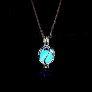 Close-up of luminous planet pendant with blue glowing bead in hollow silver cage