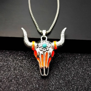 Detail of bull skull pendant with turquoise bead and red enamel on a silver square chain