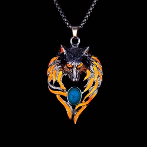 Close-up of wolf head pendant with orange flame patterns and turquoise stone detail