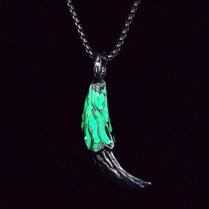Macro shot of glow-in-the-dark wolf fang pendant with green fluorescent coating and black metal