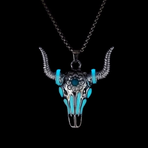Close-up of luminous bull skull pendant with gothic floral engraving in the dark