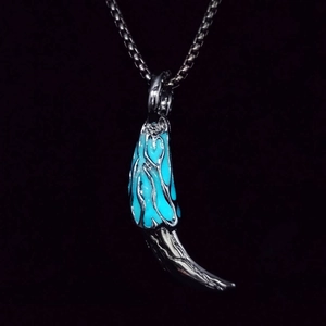 Detailed view of the luminous wolf tooth pendant with blue glow and silver flame patterns