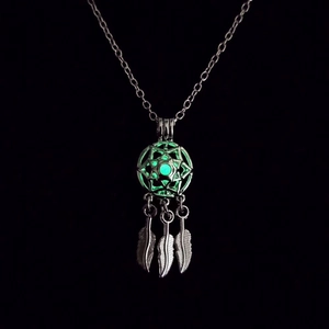 Collier attrape-rêves lumineux avec plumes argentées et pendentif brillant dans le noir