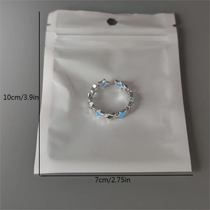 Detail of silver luminous star ring showing blue enamel patterns in packaging