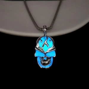 Detailed close-up of a hollow punk skull pendant with bright blue glow-in-the-dark feature