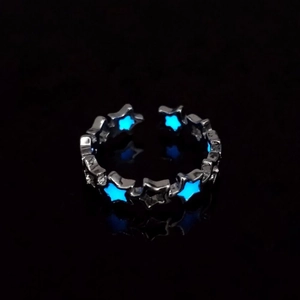 Macro shot of luminous hollow star ring with glowing ice blue light in the darkness