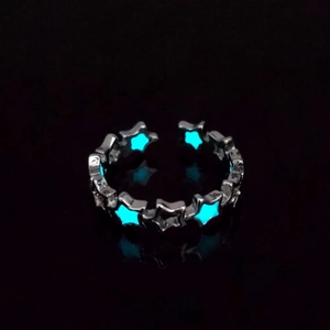 Close-up of luminous star ring glowing in dark with blue fluorescent hollow design