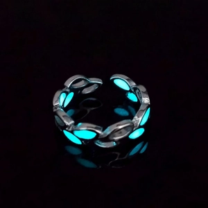 Detailed macro view of glowing blue leaf ring with adjustable silver open band design