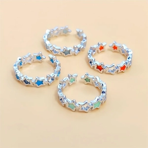 Luminous star rings in silver metal with colorful enamel inlay on soft pink background