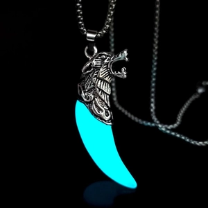 Detail of a luminous blue wolf tooth pendant with a silver metallic wolf head for men