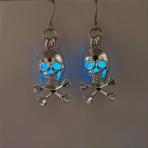 Detail shot of silver skeleton skull earrings with glowing blue luminous eye sockets