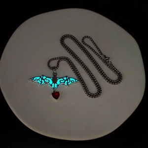 Gothic luminous bat necklace featuring a glowing blue wing and red heart crystal pendant
