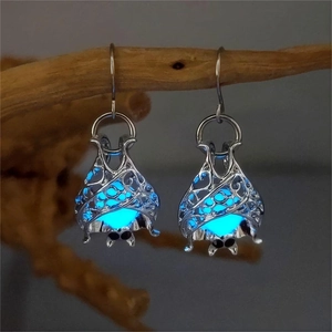 Detailed close-up of glow-in-the-dark bat earrings with blue beads on wooden branches
