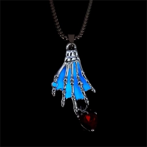 Primer plano del colgante mano de esqueleto con corazón azul brillante y circón rojo