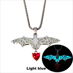 Detailed view of gothic glowing bat necklace with red heart stone and light blue luminescence