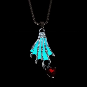 Primer plano de colgante de mano de esqueleto gótico con circón de corazón rojo y efecto neón