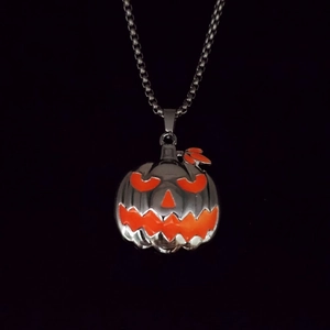 Detail view of a Halloween pumpkin face pendant on a metallic bead chain necklace