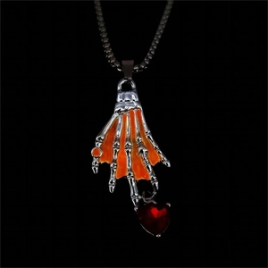 Detalle de colgante de mano de esqueleto con corazón de circonita roja y tonos naranja