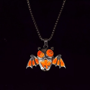 Macro shot of Halloween bat pendant with glowing orange enamel wings and box chain