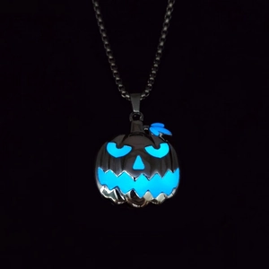 Macro shot of Halloween pumpkin charm glowing with bright blue light in the dark night