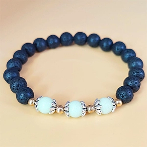 Detailed macro of black lava stone beads with light green luminous accents and silver lotus spacers
