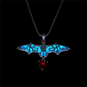 Macro detail of gothic glow-in-the-dark bat pendant with a red heart glass crystal stone