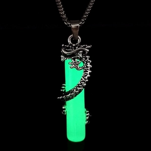 Detailed macro of vintage alloy dragon pendant with glowing green cylinder and chain