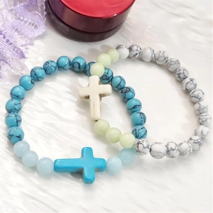 Set di bracciali per coppia con croce luminosa e perle turchesi su sfondo con onde bianche
