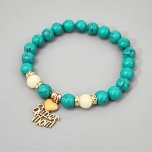 Detail view of turquoise beads with golden Super Mom charm and glowing heart pendant