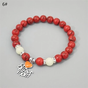 Close-up of red turquoise beads and Super Mom glowing heart charm on jewelry