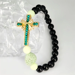 Bracelet tressé lumineux avec pendentif croix verte et perles sur fond de glace claire