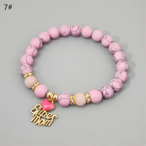 Close-up of pink marble beads and golden Super Mom heart charms on an elastic bracelet