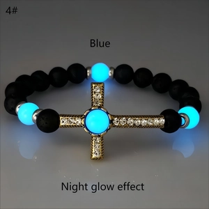 Macro di perle blu luminose e croce dorata su bracciale di pietra lavica nera