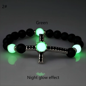 Dettaglio del bracciale di perle nere opache con sfere luminose verdi e croce di strass
