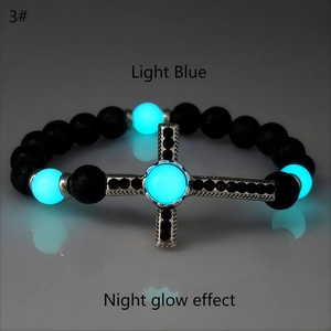 Dettaglio del bracciale croce vintage luminoso con perle di pietra lavica e bagliore blu